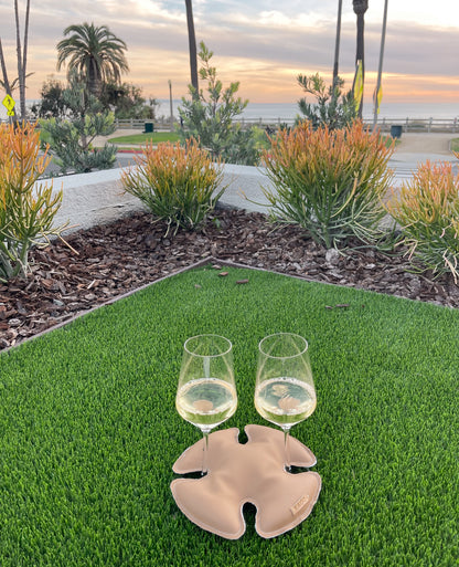 Two stemmed glasses of chilled wine stabilized between LAGO on a yard overlooking the ocean in Santa Monica.